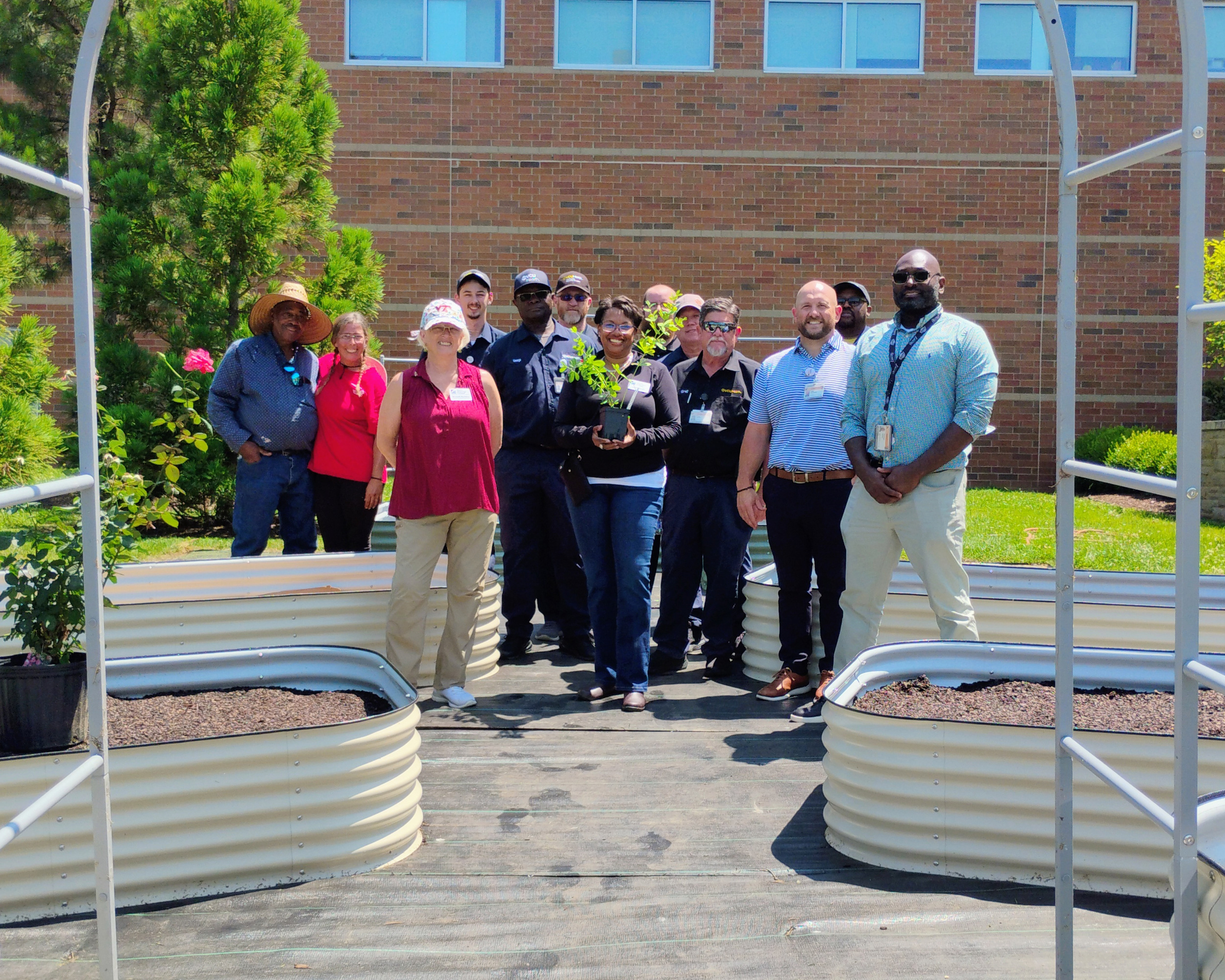 people smiling while standing with a raised garden bed